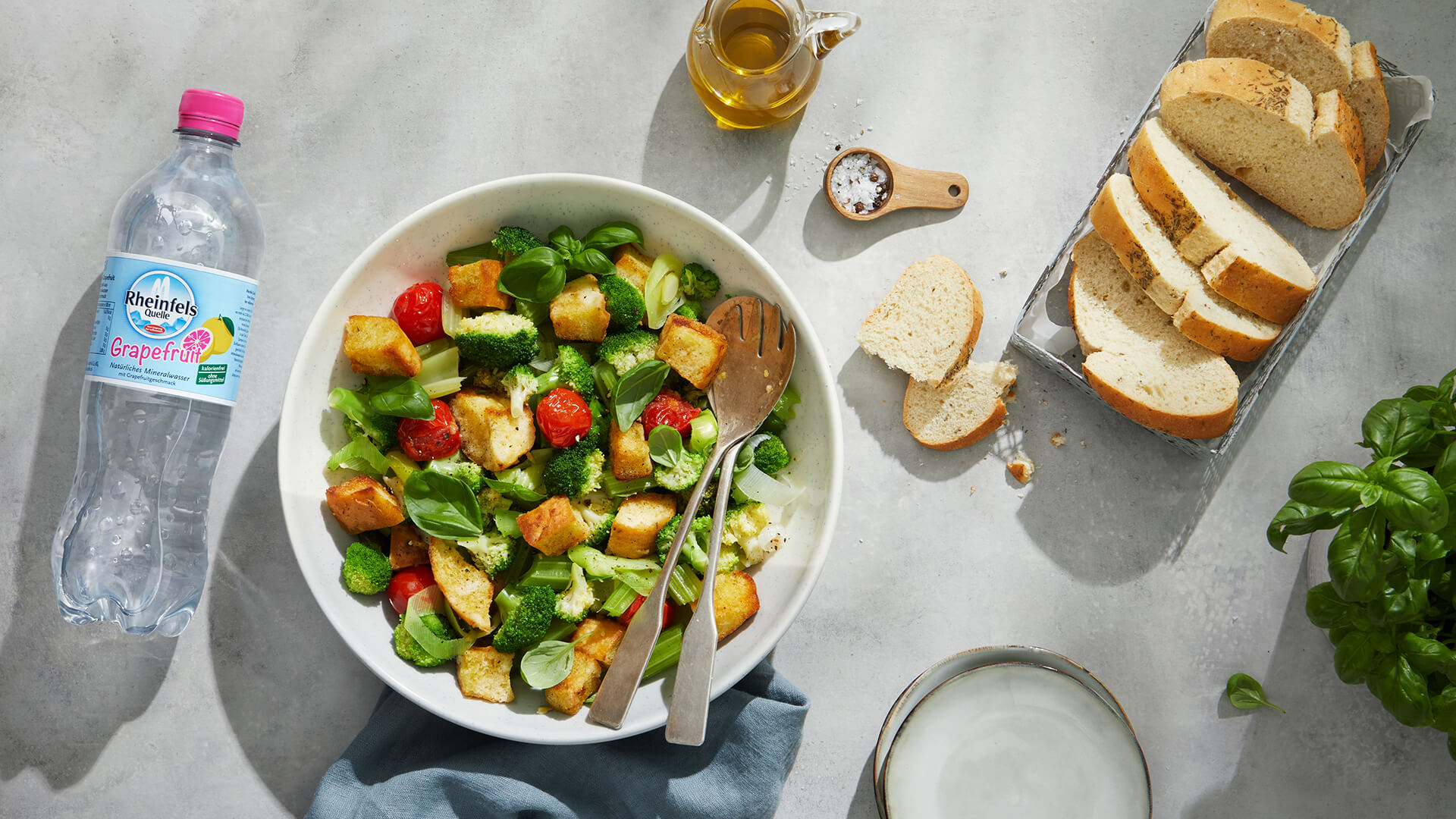 Brotsalat mit grünem Gemüse und eine Flasche Rheinfels Quelle Grapefruit