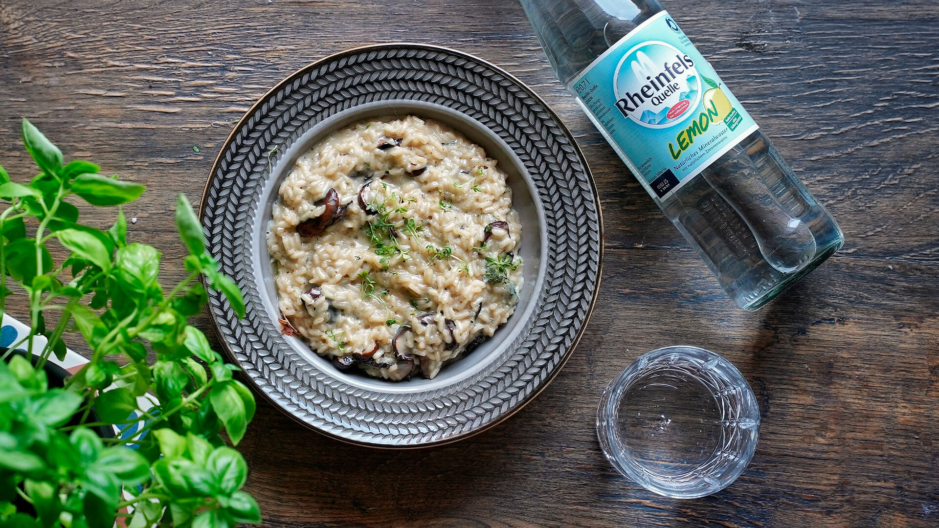 Pilz-Risotto mit einer Rheinfels Quelle Lemon Flasche