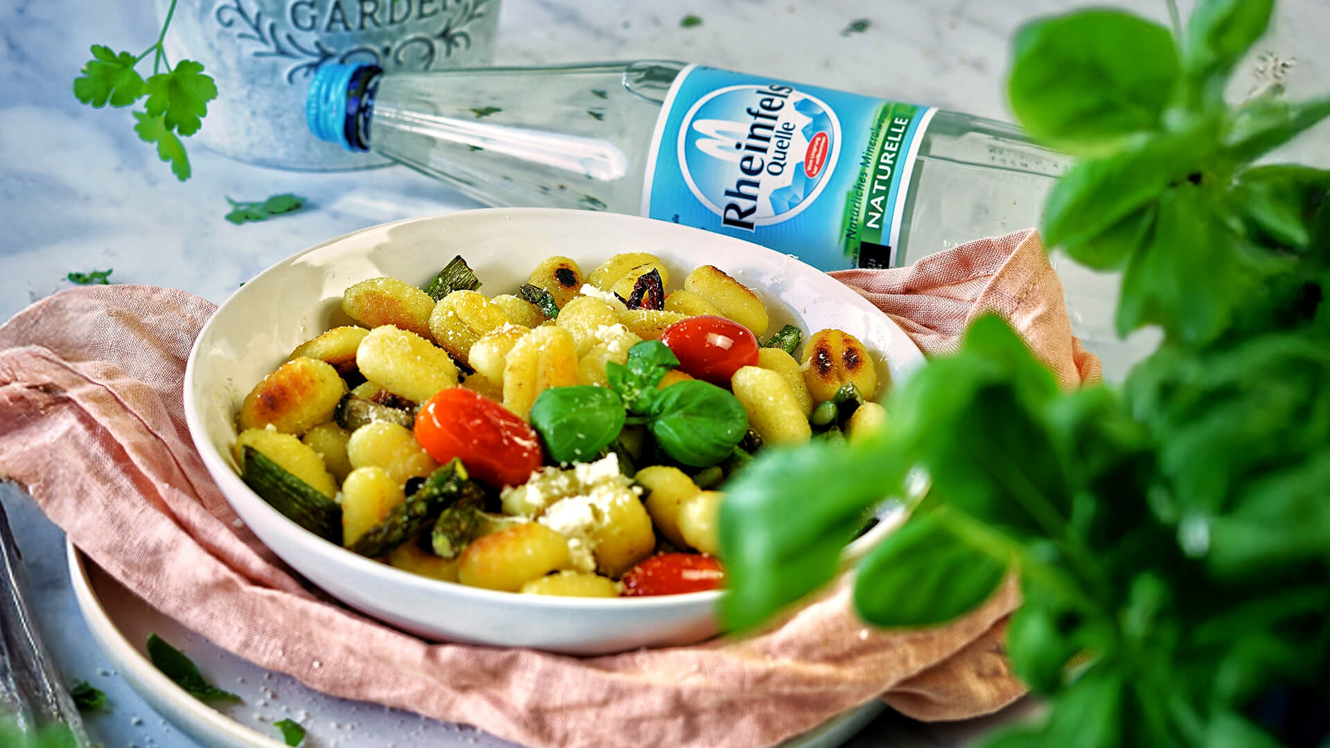 Spargel-Gnocchi-Pfanne mit einer Rheinfels Quelle Naturelle Flasche