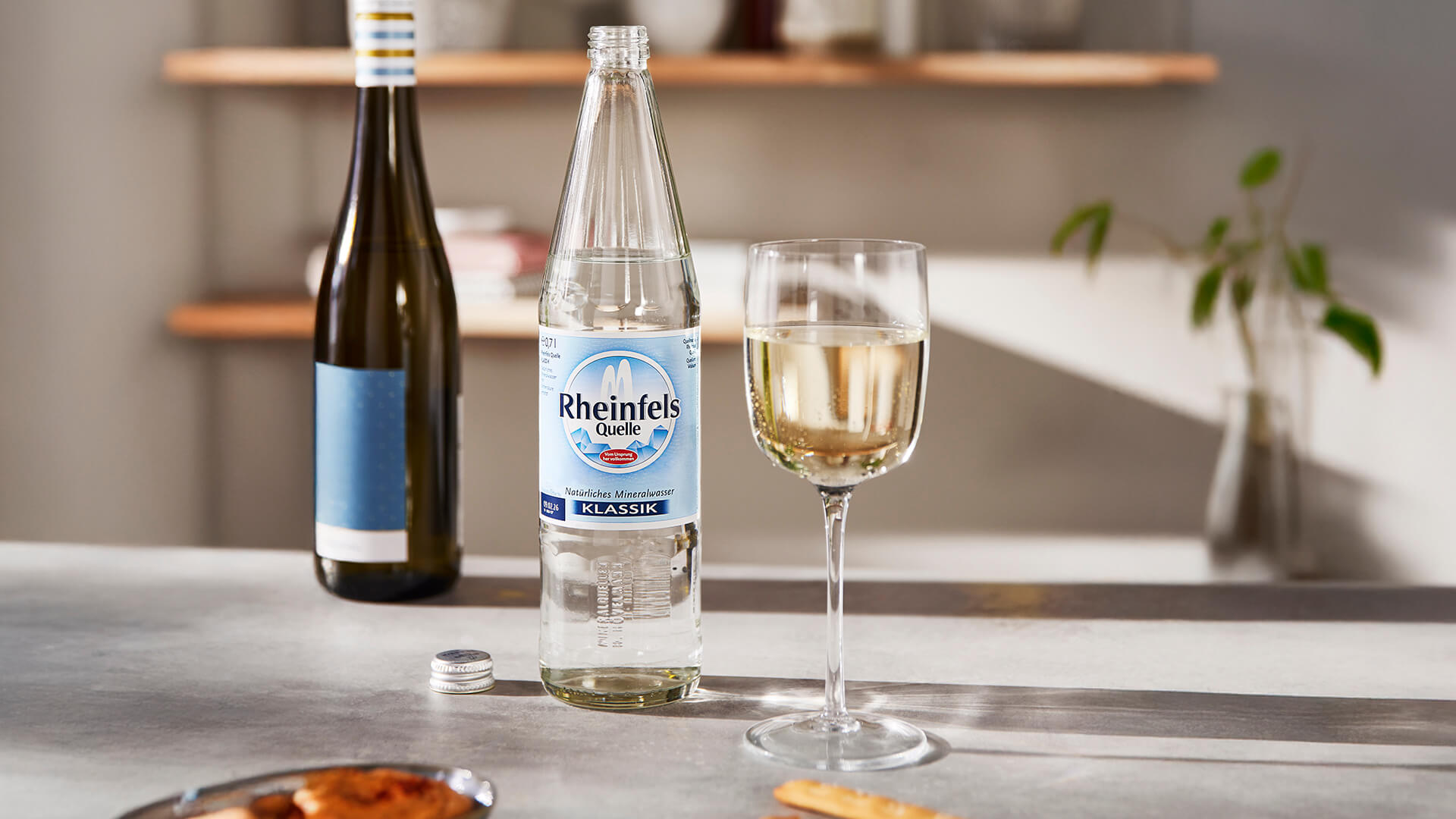 Ein Glas Weißweinschorle und ein Flasche Rheinfels Quelle Klassik